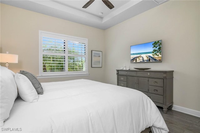 bedroom featuring ceiling fan, dark hardwood / wood-style floors, and a raised ceiling