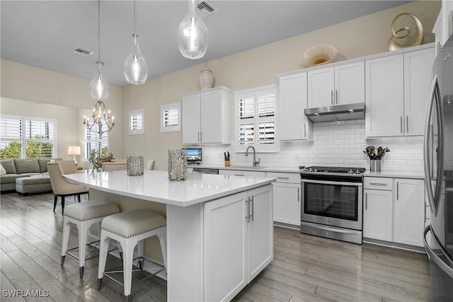 kitchen with white cabinetry, hanging light fixtures, and appliances with stainless steel finishes