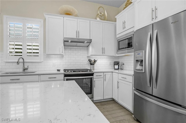 kitchen featuring light stone counters, sink, white cabinetry, and stainless steel appliances