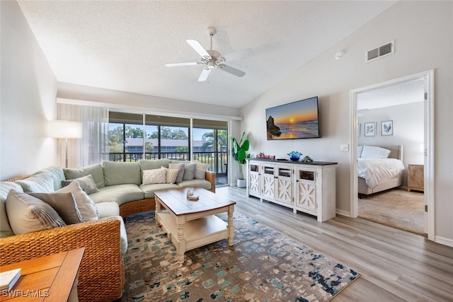 living room featuring ceiling fan, wood-type flooring, high vaulted ceiling, and a textured ceiling