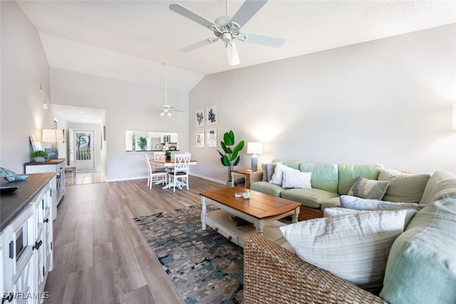 living room featuring ceiling fan, high vaulted ceiling, and light hardwood / wood-style flooring