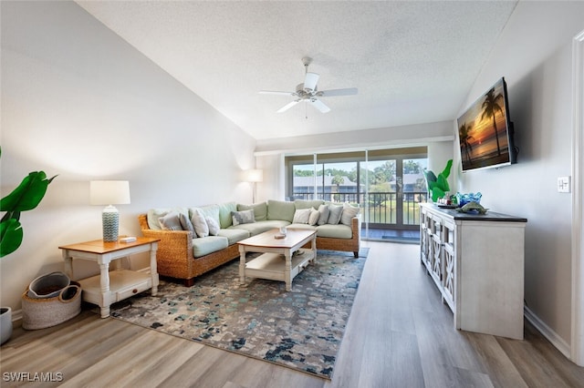 living room with lofted ceiling, hardwood / wood-style floors, a textured ceiling, and ceiling fan