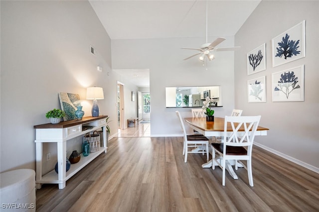 dining room with a high ceiling, sink, hardwood / wood-style floors, and ceiling fan