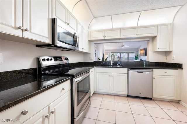 kitchen with dark stone countertops, stainless steel appliances, sink, and white cabinets