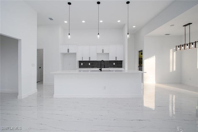 kitchen featuring a large island, sink, decorative light fixtures, and white cabinets