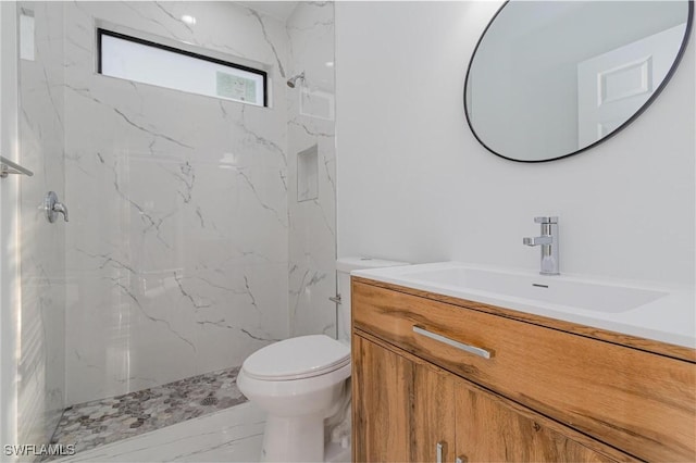 bathroom with vanity, toilet, and tiled shower