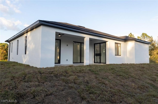 rear view of house with a yard and ceiling fan