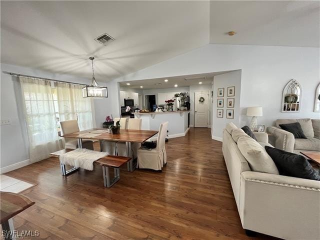 dining area with lofted ceiling, dark hardwood / wood-style floors, and a notable chandelier