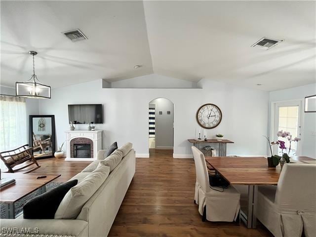 living room with a notable chandelier, plenty of natural light, dark wood-type flooring, and lofted ceiling