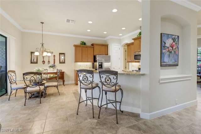 kitchen with stainless steel appliances, light stone countertops, pendant lighting, ornamental molding, and kitchen peninsula