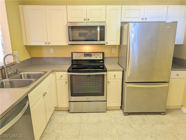 kitchen featuring stainless steel appliances, sink, light tile patterned floors, and white cabinets