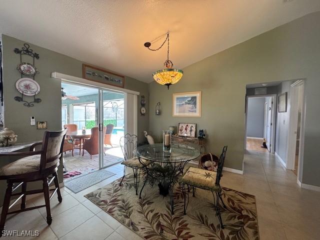 tiled dining area featuring vaulted ceiling and a textured ceiling