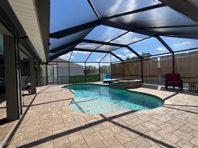 view of swimming pool with an in ground hot tub, glass enclosure, and a patio