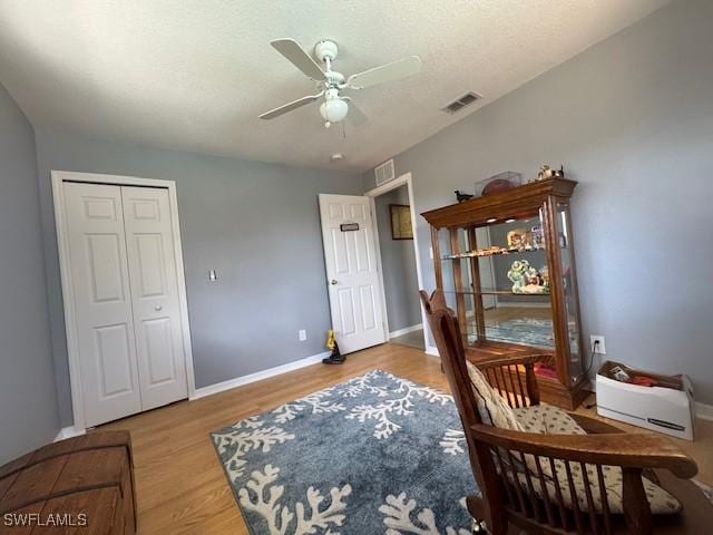 sitting room featuring ceiling fan, wood-type flooring, and a textured ceiling