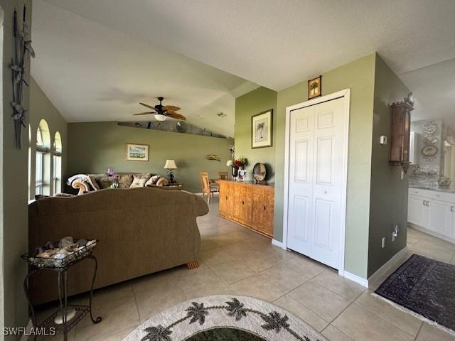 tiled living room featuring lofted ceiling and ceiling fan