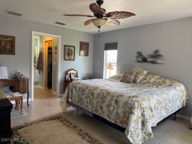 bedroom with a walk in closet, tile patterned floors, ceiling fan, and a closet