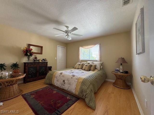 bedroom featuring ceiling fan, a textured ceiling, and light wood-type flooring