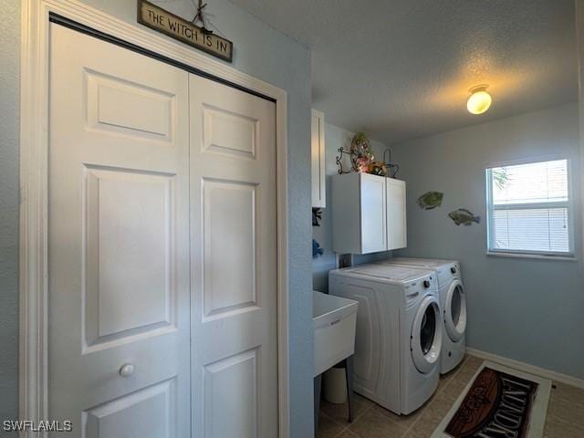 laundry room with light tile patterned flooring, cabinets, a textured ceiling, and washing machine and clothes dryer