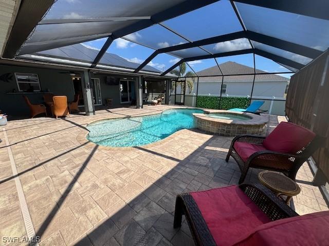 view of pool with an in ground hot tub, a lanai, and a patio