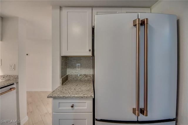 kitchen featuring high end fridge, white cabinets, and light stone counters