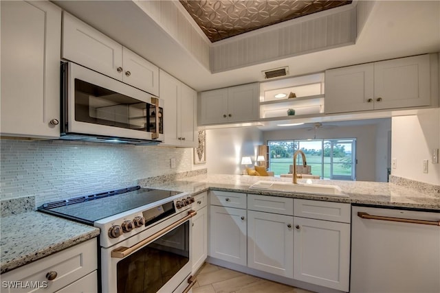 kitchen featuring stainless steel range, dishwashing machine, sink, and white cabinets