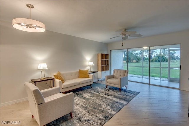 living room featuring ceiling fan with notable chandelier and light hardwood / wood-style flooring