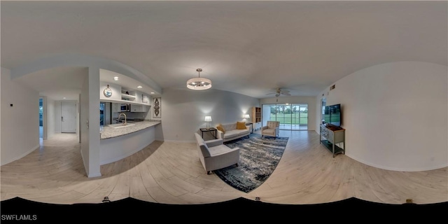 living room with vaulted ceiling, ceiling fan, sink, and light wood-type flooring