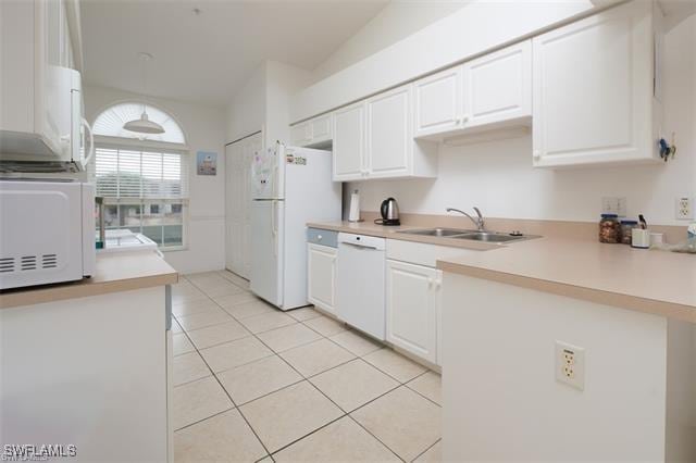 kitchen featuring pendant lighting, sink, white appliances, light tile patterned floors, and white cabinetry