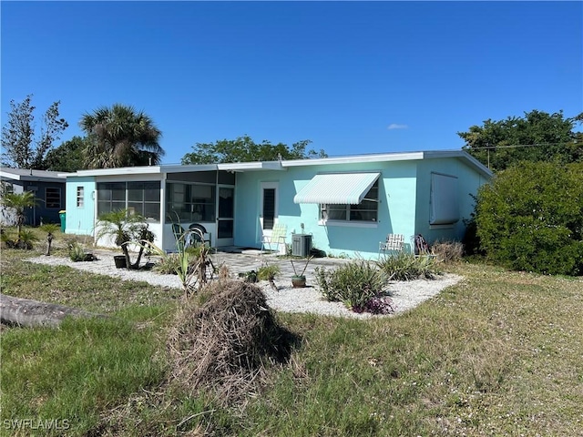 rear view of property featuring a lawn, a patio, a sunroom, and central air condition unit