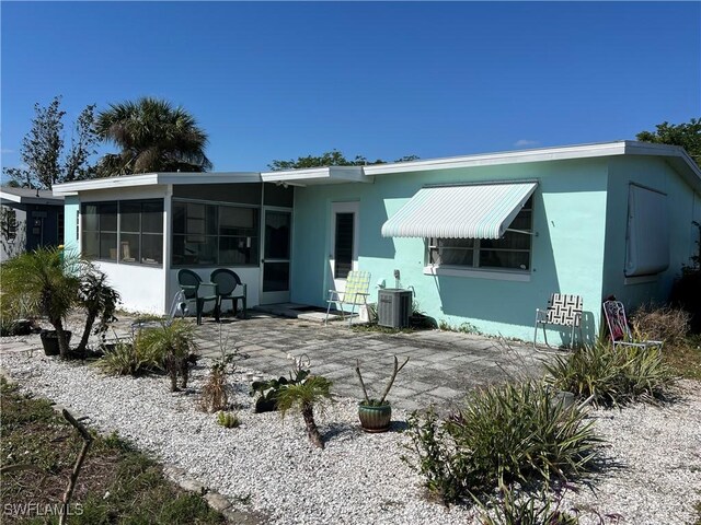 back of property with a sunroom, a patio, and central air condition unit