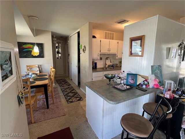 kitchen featuring white cabinetry, sink, a breakfast bar area, and hanging light fixtures