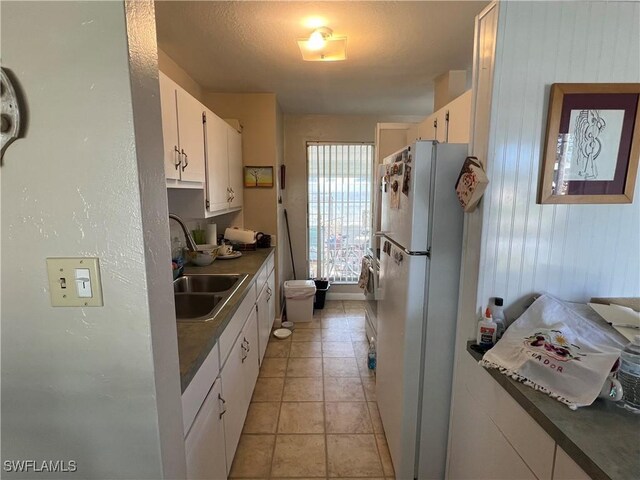 kitchen featuring white cabinetry, sink, light tile patterned floors, and white fridge