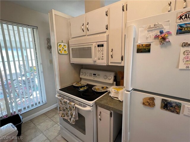 kitchen with white cabinetry, white appliances, plenty of natural light, and light tile patterned flooring