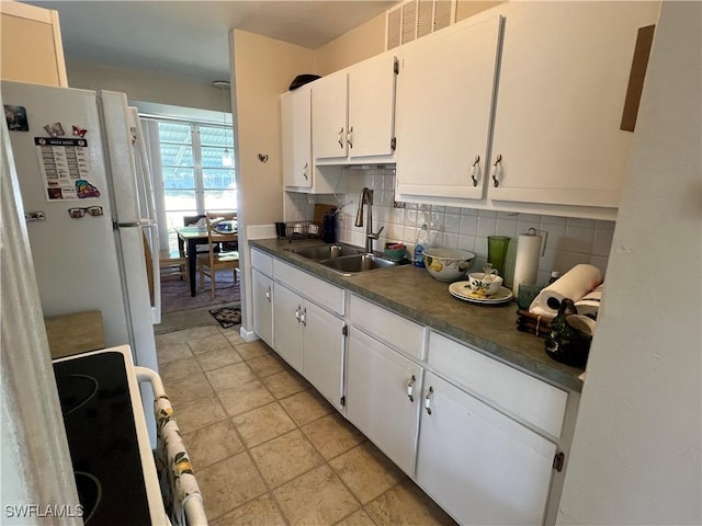 kitchen featuring electric range oven, tasteful backsplash, white cabinetry, sink, and white refrigerator