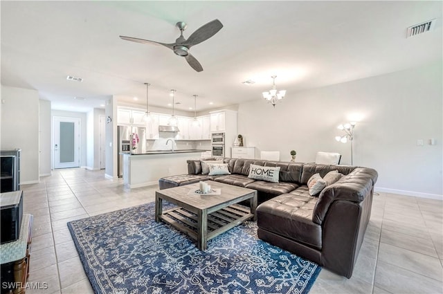 living room featuring ceiling fan with notable chandelier, sink, and light tile patterned floors