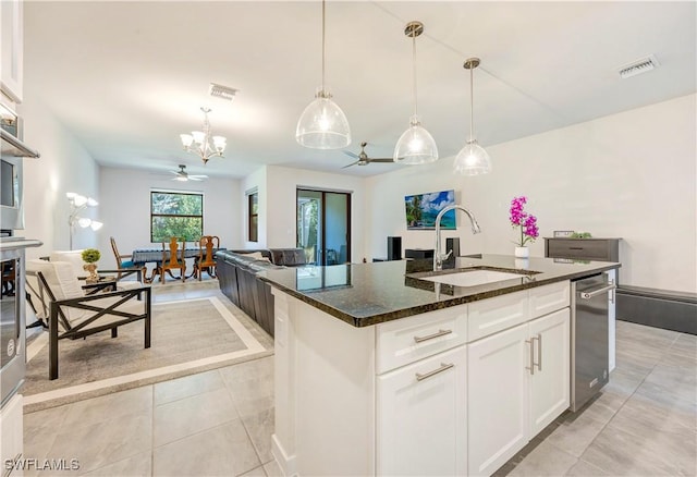 kitchen featuring sink, dark stone countertops, white cabinets, a center island with sink, and decorative light fixtures