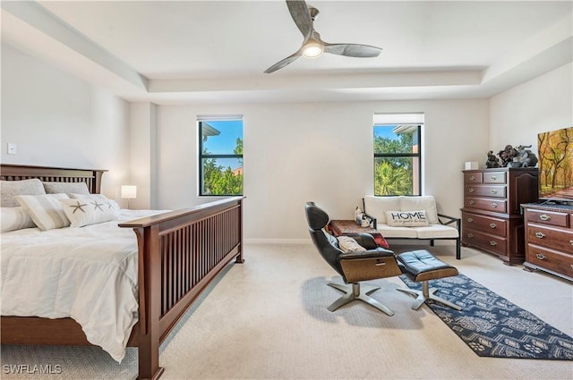 carpeted bedroom featuring a raised ceiling and ceiling fan