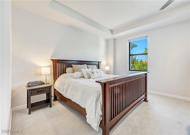 bedroom with light colored carpet and a raised ceiling