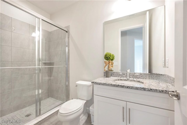 bathroom with vanity, a shower with door, and toilet