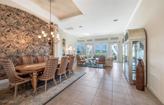 dining space with crown molding, a notable chandelier, a tray ceiling, and light tile patterned floors
