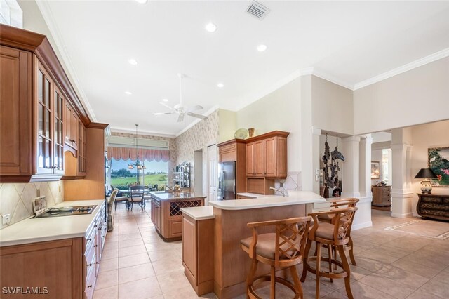 kitchen featuring crown molding, decorative columns, a kitchen island, stainless steel fridge with ice dispenser, and kitchen peninsula