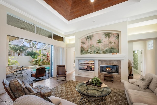 tiled living room featuring a tiled fireplace, a tray ceiling, ornamental molding, and a high ceiling