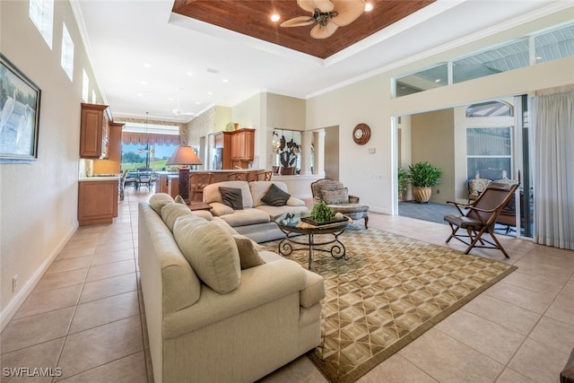 living room with crown molding, light tile patterned floors, a raised ceiling, ceiling fan, and a high ceiling