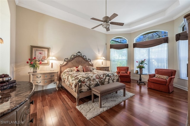 bedroom with crown molding, dark wood-type flooring, ceiling fan, and a tray ceiling