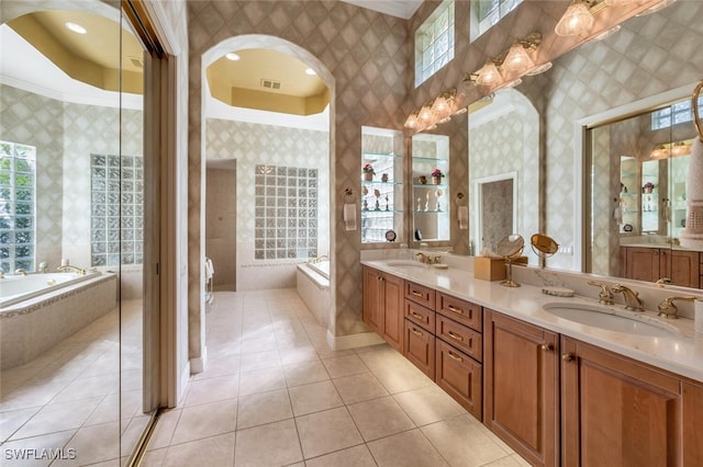 bathroom with tile patterned flooring, vanity, ornamental molding, and tiled bath