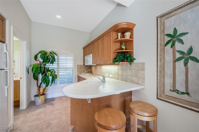 kitchen featuring tasteful backsplash, a breakfast bar area, white appliances, and kitchen peninsula