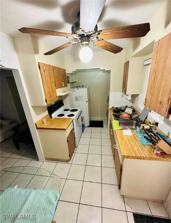 kitchen featuring light tile patterned flooring, sink, ceiling fan, white appliances, and decorative backsplash