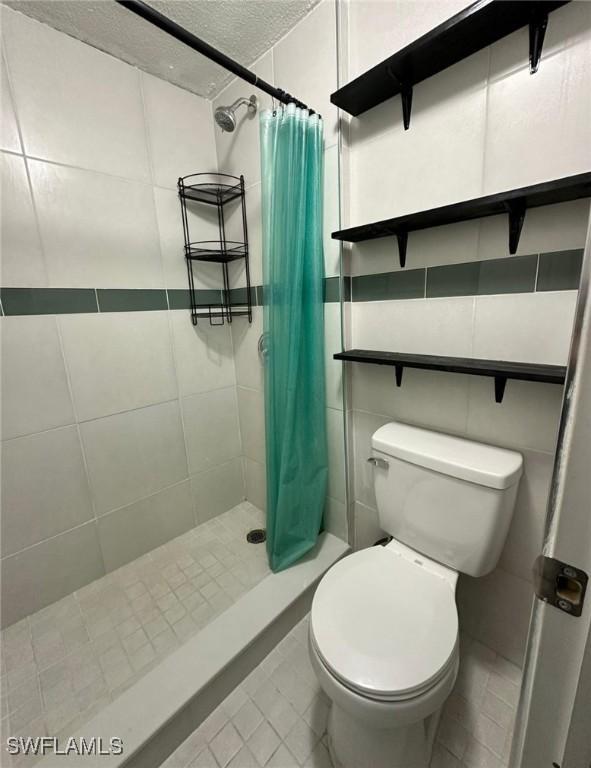 bathroom featuring tile patterned flooring, a shower with curtain, a textured ceiling, and toilet