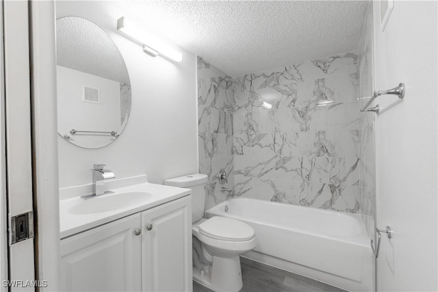 full bathroom with tiled shower / bath, vanity, toilet, and a textured ceiling