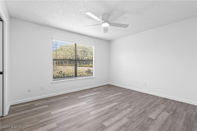 empty room with ceiling fan, light hardwood / wood-style floors, and a textured ceiling